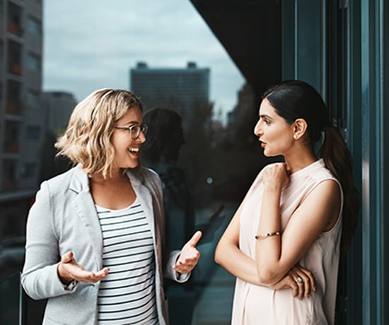 Shot of two businesswomen having a discussion on the office balcony