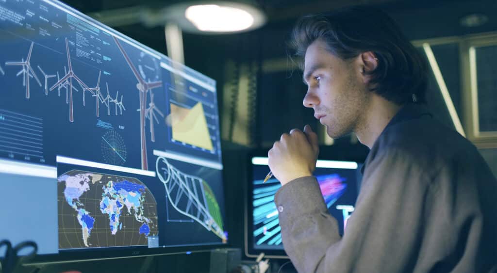 Engineer working in front of muilple screens displaying wind turbines and other metorlogical diagrams