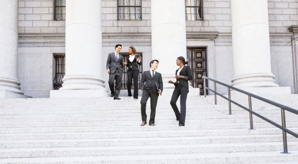 Four professionals conversing on the steps of a government building