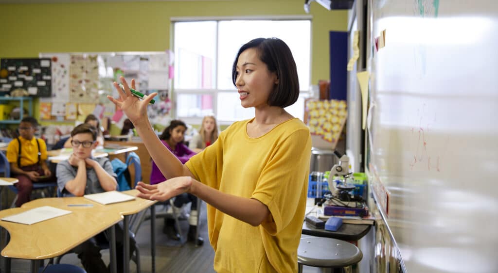 Photo of teacher facing students while demonstrating with hands