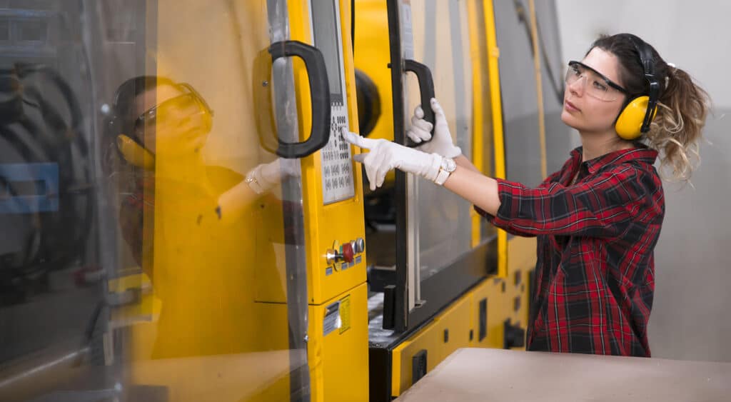 Machine operator pressing a key pad while wearing personal protective equipment