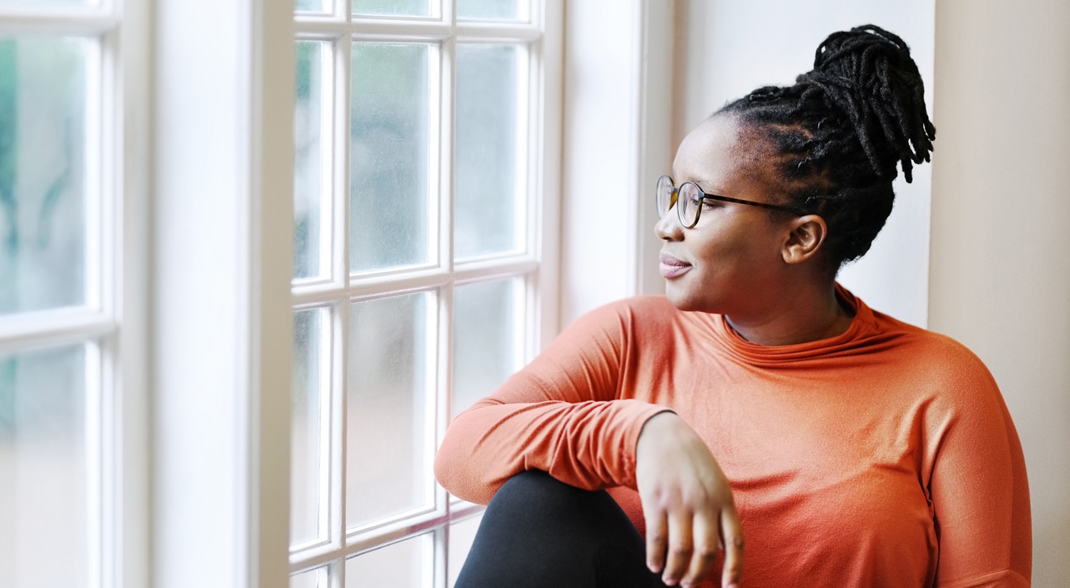 Woman sitting on window sill reflecting