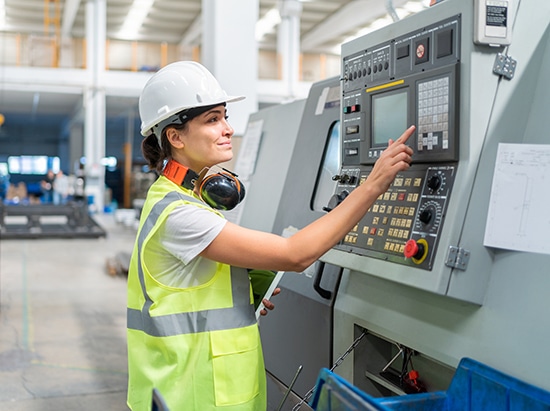 Ingeniera programando una máquina CNC en fábrica