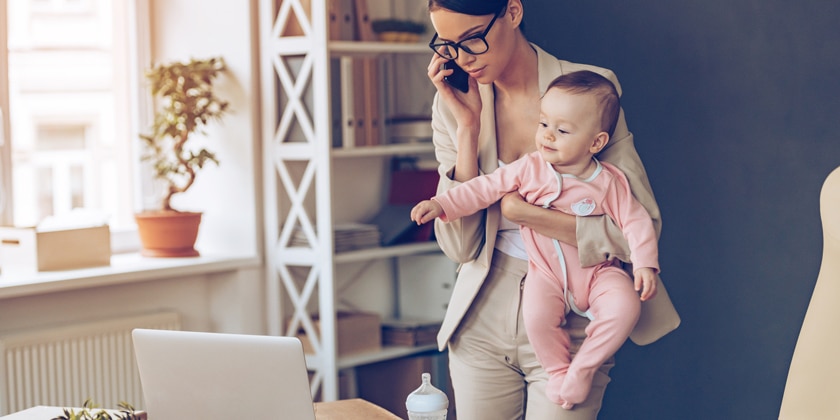 woman holding a toddler while talking on a cell phone