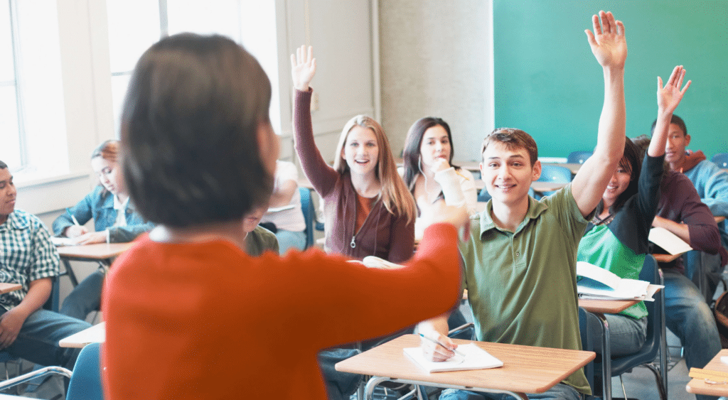 Teacher calling on students with hands raised.